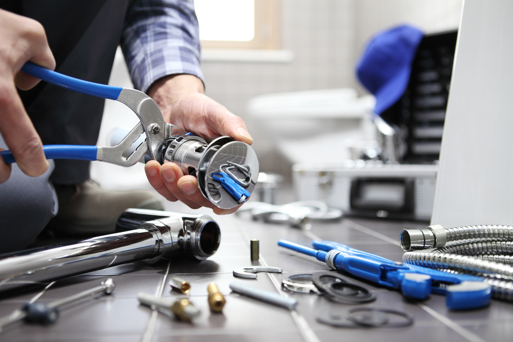 Plumber repairing bathroom sink drain with professional tools - Plumbing Champions